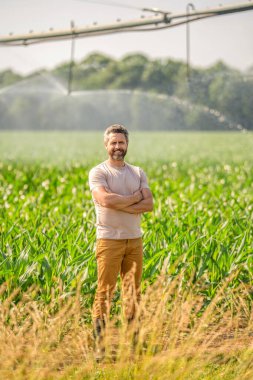 Çiftçi adam. Su püskürtme sulama tarlası. Damlatma sulama sistemi. Ekin sulama. Tarım ve tarım. Sulama sisteminde tarımı sulayan bir adam. Fıskiye sulama.