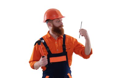 Üniformalı tamircinin çekici var. Çekiçle sakallı tamirci. Marangoz, beyaz çiviyle tamir ediyor. Tamirci. Adam çekiç çivisi tutuyor. Marangozluk ve onarım.