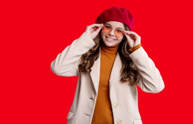 Sonbahar tarzının modaya uygun portresi. Sonbahar montlu kız kırmızıda izole edilmiş. Genç kız ceket giyiyor. Sonbahar moda kızı. Moda ve şık bir genç kız. Gençler için sonbahar moda tarzı. Moda ilerlemesi açıklaması.