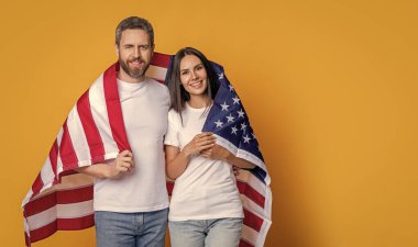 Bir çift Amerikan bayrağıyla gururla poz veriyor, fotokopi uzayı. Amerikan bayrağı taşıyan çiftlerin vatanseverliği. Bayrağa sarılı Amerikalı ruh çifti kutluyoruz. Bayrağı olan Amerikalı çift..