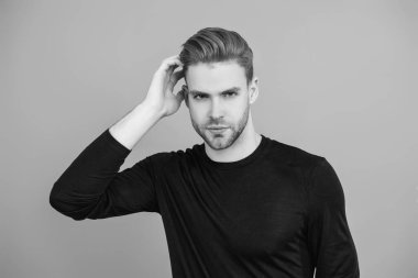 Adamın şık bir saç kesimi var. Moda saç stili olan bir adam. Sıradan erkek tarzı. Beyazlı genç bir adam gri yolda izole edilmiş. Kendine güvenen adam portresi. Erkeklerin cilt bakımı. Erkek derisi. Kuaför..
