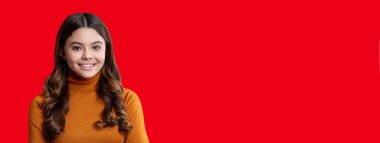 Sıradan süveter giyen şık bir kız. Genç kız kırmızıda izole edilmiş günlük kıyafet giyer. Moda kızı portresi. Modayı takip eden bir genç. Gençler için moda tarzı. Kızın portresi kıvırcık saçlı. Boşluk afişini kopyala