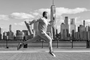 Spor takım elbiseli bir adam dışarıda spor yapmak için spor minderiyle Manhattan 'da koşuyor..