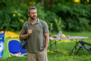 Yaz kampı. Kamp macerası. Yürüyüş yaşam tarzı. Kamp alanındaki adam. Piknik zamanı reklamı. Ormanda çadırlı piknik yapan bir adam. Yaz günü yürüyüş yapan bir adam. Yaz kampı aktivitesi.