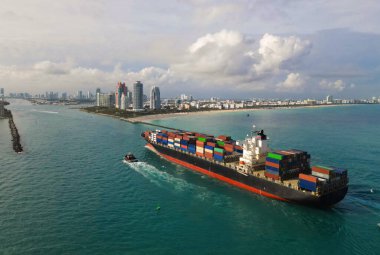 Kargo gemisi limandan ayrılıyor. Konteyner gemisi. İhraç ve ithalat. Kargo işi. Miami Limanı. Konteynırlı kargo gemisi, hava manzaralı. Kargo gemisinde nakliye konteynırı. Tam yük ile yelken aç.