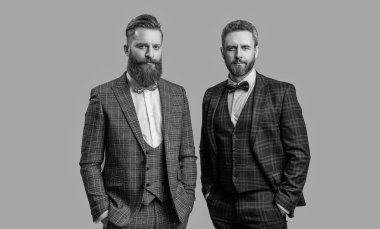 Smokinli adamlar gri alanda izole edilmiş. Erkek giyim bölümünde smokin giyen adamlar. Smokinli erkekler erkek giyim tarzı giyinir. Papyonlu şık giyinen şık adamlar. İş etkinliğindeki iki iş adamı. Klasik erkek giyim..