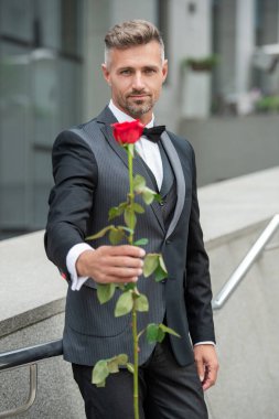 Siyah smokinli zarif adam. Adam dışarıda smokin papyon takıyor. Kırmızı güllü yakışıklı smokinli adam..