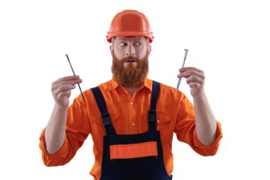 Marangoz, beyaz çiviyle tamir ediyor. Tamirci. Adam çekiç çivisi tutuyor. Marangozluk tamir ve çekiç. Üniformalı tamircinin çivisi var. Sakallı marangoz çivi tutar. Genel DIY araç seti.