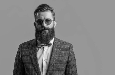 Smokinli, sakallı, şık erkek giyimli, takım elbiseli ve papyonlu bir adam. Gri, fotokopi alanında izole edilmiş..