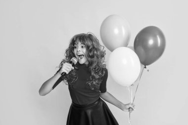 Sarı arka planda parti balonu ve mikrofonlu çocuk gülümsemesi.