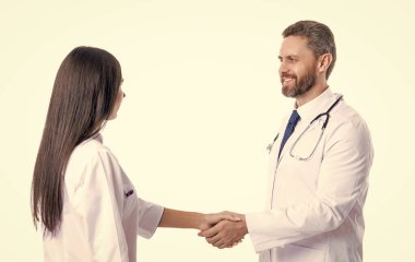 Hastane takım çalışması işbirliği. Başarılı tedavi. Doktor, hemşireyle tokalaşıyor. İki doktor beyazın üzerinde el sıkışıyor. Tokalaşma, hasta sağlığı konusunda anlaşma. Tokalaşma adabı.