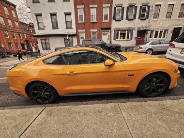 New York, ABD - 10 Mart 2024: 2018 Ford Mustang sarı spor arabası, yan görüş.