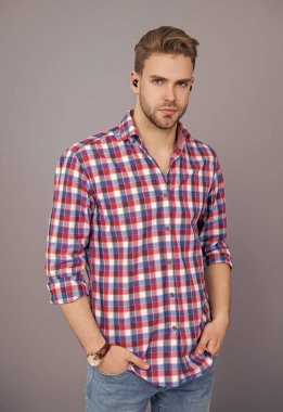 Kablosuz kulaklıklı bir adam. Adam gri renkte izole edilmiş kulaklık kullanıyor. Modern kablosuz kulaklıklar. Elsiz kulaklık. Kulaklık cihazı aksesuarı. Kablosuz kulaklık cihazı. Kulaklık aksesuarları. Aletli adam..