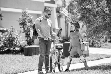 Baba ve oğlunun babalığı güneşli parkta bisiklet sürüyor. Baba oğul birlikte dolambaçlı yollarda yol alırlar. Baba-oğul gezintisi. Baba ve oğul babalığında. baba desteği.