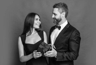 Erkek kadına evlenme teklif ediyor. Erkek, sevgililer günü için kadınlara hediye kutusu verir. Sevgililer günün kutlu olsun. Aşık çift kırmızıda izole edilmiş. Hediyeli romantik evlenme teklifi. Hediye. Romantik teklif.