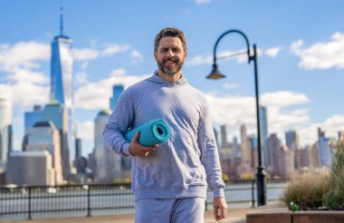 Vücuduna uygun. Yoga koçu. Sporcu adam antrenmana hazır. Sağlıklı bir yaşam tarzı. Spor ve spor. Eğitim için yoga minderi. New York 'ta sporcu. Manhattan 'da spor kıyafetli bir adam. NY yoga.