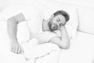 Uykulu adam beyaz yatak odasında uyuyor. Uyuyan genç adam uyuyor. Rahat bir yatakta huzur içinde dinleniyor. Kapalı gözlerle yalan söylemek. Derin erkek uykusu. Geceleri uyuyan bir adam. Huzurlu bir uyku..