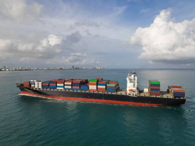 Hava görüntülü kargo gemisi limana giriyor. Kargo işi. Konteyner gemisi. Nakliye lojistiği. Kargo gemisi denizde, hava manzaralı. Yük konteynırı kargo gemisine yüklendi. Yük konteynırları üst üste dizildi.