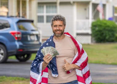 Amerikan vergi politikası. İspanyol adam ve Amerikan bayrağı. Amerika 'da vergi ödemek. Katma değer vergisi. Vergi sistemi. Vatansever adam. Amerikan bayrağı ve dolar parası olan adam. Enflasyon konsepti. Başparmak yukarı..