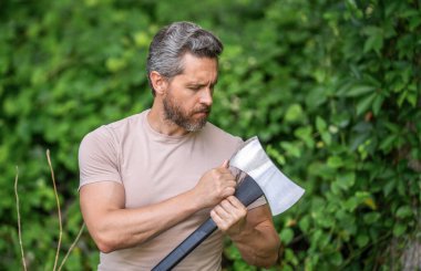 Çalışkan vahşi adam keskin bıçağı kontrol ediyor. Oduncu dışarıda çok çalışıyor. Acımasız oduncu. Vahşilik ve erkeklik. Baltalı İspanyol oduncu adam. Oduncu baltası. Ağaç kesen baltalı adam..