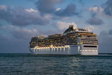 Gece vakti ışıltılı lüks yolcu gemisi yolculuğunun havadan görünüşü. Gemi Miami sahil limanından ayrılıyor. Gemi seyahati. Yaz tatilindeki deniz yolculuğunun havadan görünüşü. Gemi turu ve deniz yolculuğu..