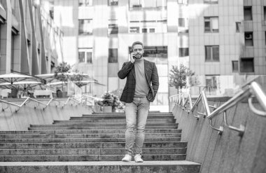 Uzun boylu bir adamın sokakta cep telefonu araması. Dışarıdaki cep telefonundan arayan bir adam. Adamın cep telefonundan aradığı ve konuştuğu fotoğraf. Adamın dışarıda cep telefonu görüşmesi var..