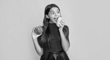 Sarı zemin üzerinde taze elma ve armut olan hayrete düşmüş çocuk..