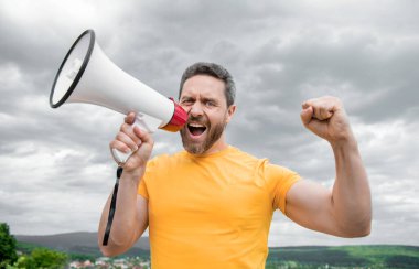 Sarı gömlekli adam gökyüzünde hoparlörden anons yapıyor..