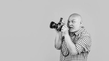 glad mature man with retro photo camera on yellow baqckground.