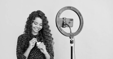 cheerful child with long curly hair making video for blog hold powder brush.