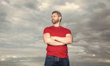 Confident guy sky background. Serious guy keeping arms crossed. Grizzled guy in casual outdoors.