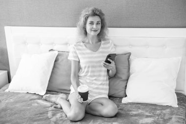 Telefonla kahve alışverişi yapan gülümseyen bir kadın. Evde telefonuyla alışveriş yapan bir kadın. Kadının evinden online alışveriş.