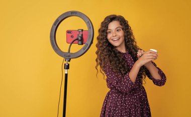 Uzun kıvırcık saçlı mutlu çocuk blogda pudra fırçası videosu çekiyor.