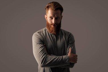 Kollarını kavuşturan kendine güvenen sakallı adam. Kızıl sakallı ve bıyıklı İrlandalı bir adam. Ciddi traşsız adam stüdyosu Griler 'de izole edilmiş..