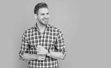 Stüdyo fotoğrafı, fotokopi alanı. Sakallı beyaz bir adam. Gri arka planda kareli gömlekli yakışıklı bir adam izole edilmiş. Gündelik tarzda bir adam..