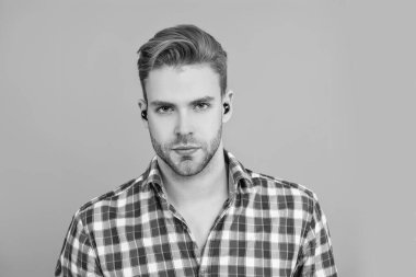 Kulaklık cihazı aksesuarı. Kablosuz kulaklık cihazı. Aleti olan bir milenyum adamı. Kablosuz kulaklıklı bir adam. Adam gri renkte izole edilmiş kulaklık kullanıyor. Modern kablosuz kulaklıklar. Elsiz kulaklık.