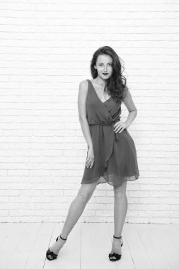 Moda elbisesi içinde genç ve güzel bir kadın. Beyaz tenli kadın, beyazın üzerinde yalnız poz veriyor. Mankenler elbise giyer. Zarif ve zarif bir kadın. Şık, sıradan tarzda şık bir kız. Çekici bayan..