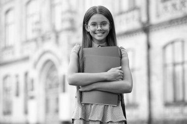 Gözlüklü kız öğrenci. Okula dönelim. Eğitim ve bilgi. Öğrenci kızın okul çantası ve egzersiz kitabı var. Açık hava ilkokulu mutlu genç kız portresi. Eğitim kaynakları.