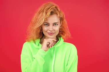 Hareketli moda kız kapüşonlu giyer. Moda kıyafetleri ve tarzı. Kazaklı beyaz bir kadın. Sıradan bir yaşam tarzı. Havalı kapüşonlu giyen kızıl saçlı kız. Pembe üzerine izole edilmiş şık bir kadın. Süper model.