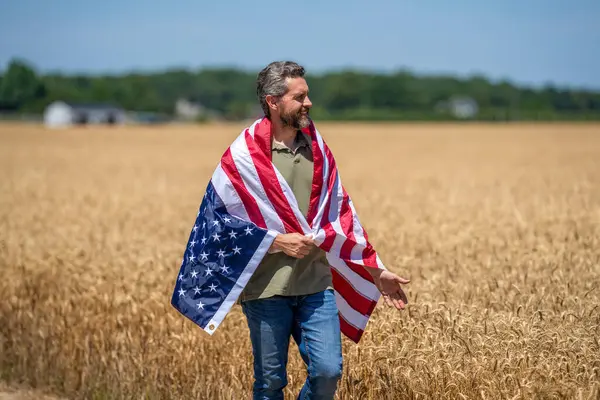 Bağımsızlık Günü. Sahadaki adam. Sahada Amerikan bayrağı taşıyan vatansever adam. Amerika 'nın Bağımsızlık Günü. 4 Temmuz. İşçi bayramı. Amerikan bayrağı ve çiftçi adam, hasat zamanı. ABD bayrağı. Anma Günü.