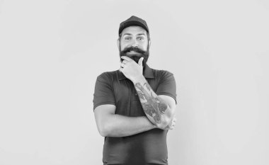 Kırmızı şapkalı ve tişörtlü mutlu sakallı adam çene okşayan sarı arka plan, teslimatçı adam.