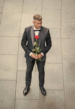 Smokinli şık bir adam. Dışarıda papyon giyen bir adam. Kırmızı güllü romantik smokinli adam..