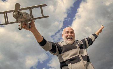 Kıdemli adam gökyüzü geçmişinde iyi eğlenceler. Emeklilikteki son sınıf. Dışarıda oyuncak uçağı olan yaşlı emekli bir adam..