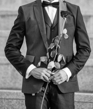 Aşk randevu konsepti. Aşk güllü smokin giyen adamın kırpılmış görüntüsü. Aşk günü için güller.