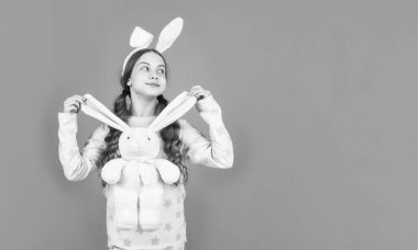 Tavşan kulaklı ve pijamalı mutlu Paskalya kızı oyuncaklarla, fotokopi yeriyle, paskalya bayramıyla oynuyor..