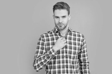 Gri arka planda kareli gömlekli yakışıklı bir adam izole edilmiş. Sıradan giyinen bir adam. Stüdyo fotoğrafı. Kafkasyalı adamın sakalı var..