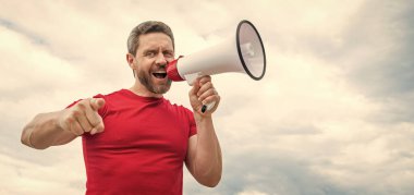man in red shirt shout in loudspeaker on sky background. copy space.