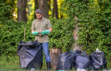 Gönüllü adam ormanda çöp topluyor. Çevresel koruma. Çevreci adam. Çevresel koruma. Çevreyi koru. Çevre plastik kirliliği. Atık toplama servisi.