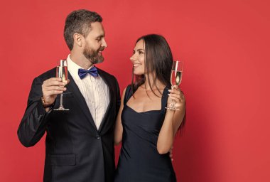 Yıldönümünü kutlayalım. Aşık çift nişanı kutluyor. Zarif çift kırmızıda izole edilmiş şampanya içer. Resmi olarak bir çift. Romantik randevu kutlamaları. Sevgililer Günü. Neşeli çift.