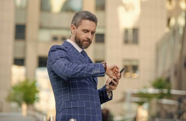 Dakik adam, nöbete geç kalma zamanını kontrol ediyor. Nöbetçi bir iş adamı. Dakik iş adamı dışarıda zamanı kontrol ediyor. İş için son gün. İş hayatına geç kalan bir iş adamı. Zaman yönetimi.